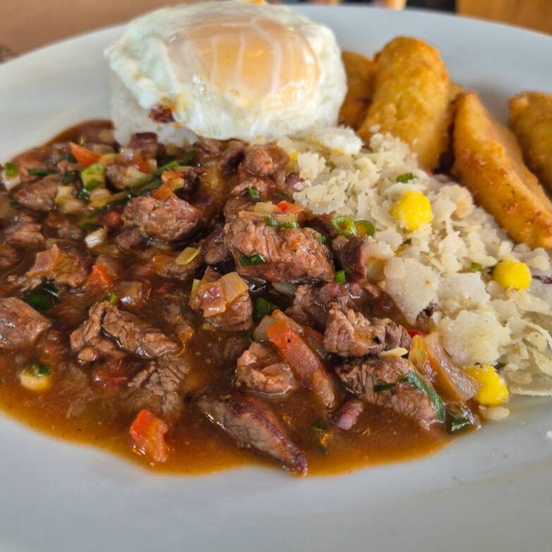 Picadinho de filet mignon, servido com arroz branco, farofa, banana a milanesa e um ovo frito.