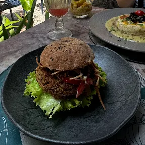 Disco feito com lentilha, arroz integral, shimeji e ervas finas, acompanha alface orgânico, cebola no shoyu daimaru, tomate organico maionese da casa e inhame palha no pão de hamburguer