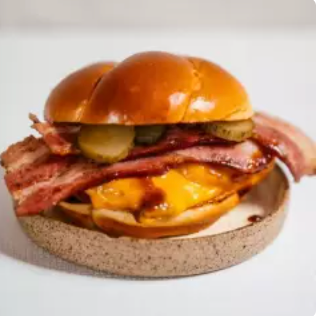 Sassami de Frango Empanado / Cheddar / Bacon Grelhado / Pickles / Molho Buffalo / Finalizado em nosso Exclusivo Pão de Brioche Artesanal.