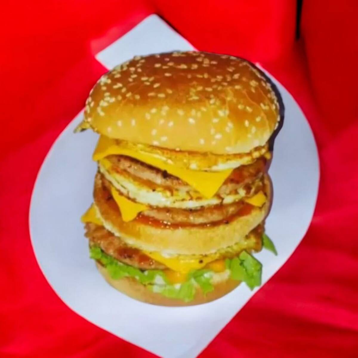 Pão , 3 carnes , bacon , ovo , 3 queijo cheddar , picles, alface , cebola roxa e molhos .