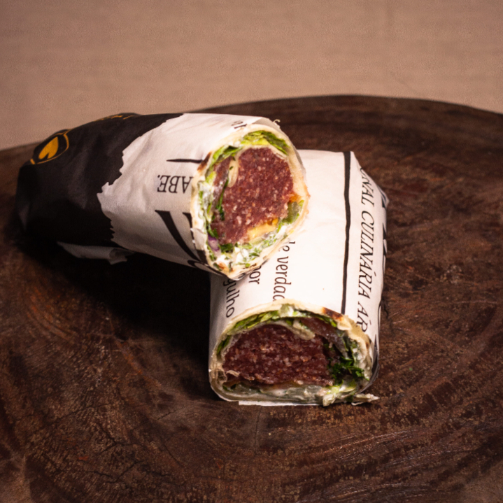 Enrolado no pão sírio com kibe cru, coalhada, picles, salsinha, cebola, alface e tomate.