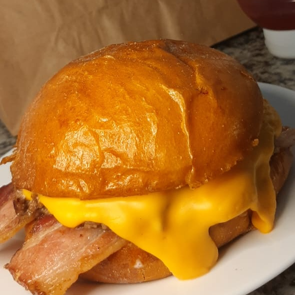 HAMBÚRGUER ARTESANAL DE 180 g, ACOMPANHADO DE QUEIJO A SUA ESCOLHA DERRETIDO, TIRAS DE BACON CROCANTE, E CEBOLA ROXA EM NOSSO DELICIOSO PÃO BRIOCHE PRODUZIDO NA CASA, E MAIONESE CASEIRA