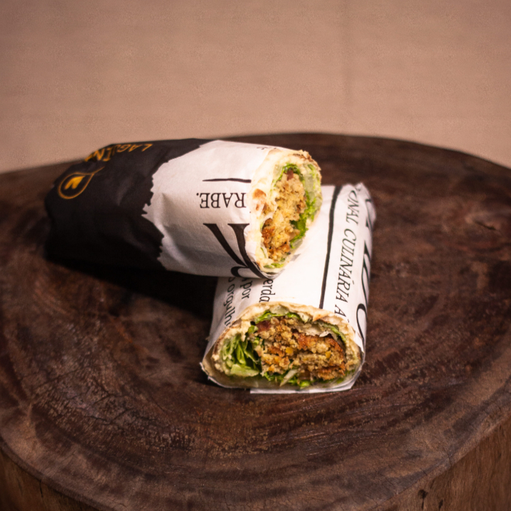 Enrolado no pão sírio com bolinhos de falafel, pasta de grão de bico, picles, salsinha, cebola, alface e tomate.