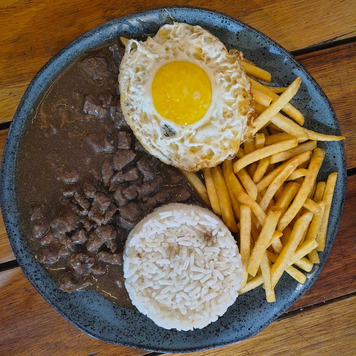 Arroz branco, carne ao molho bem temperada, ovo frito com gema cremosa e batata frita