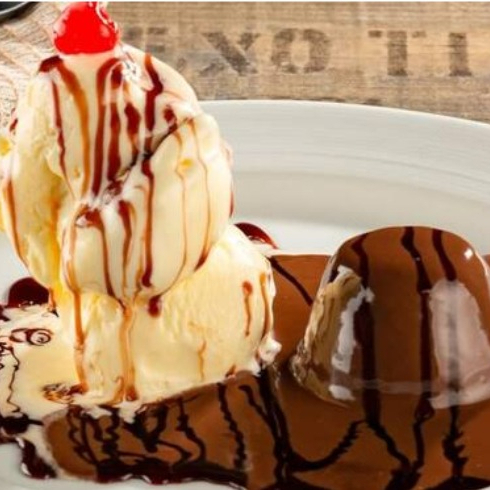 Apresentamos nosso Petit Gateau, uma estrela da categoria 'Sobremesas'. Este deleite é composto por um bolinho irresistivelmente macio, recheado com um chocolate cremoso e intenso. Cada mordida revela o prazer do chocolate derretido, criando uma experiência única. A maravilha não para por aí, pois o bolinho é generosamente coberto com uma camada de ganache de chocolate, adicionando uma doçura equilibrada e um brilho atraente. Para completar a delícia, acompanha um sorvete de creme divinamente suave e refrescante. Cada colherada irá fundir-se na sua boca, proporcionando um contraste perfeito com o chocolate quente. Um prato que encanta tanto aos olhos quanto ao paladar.