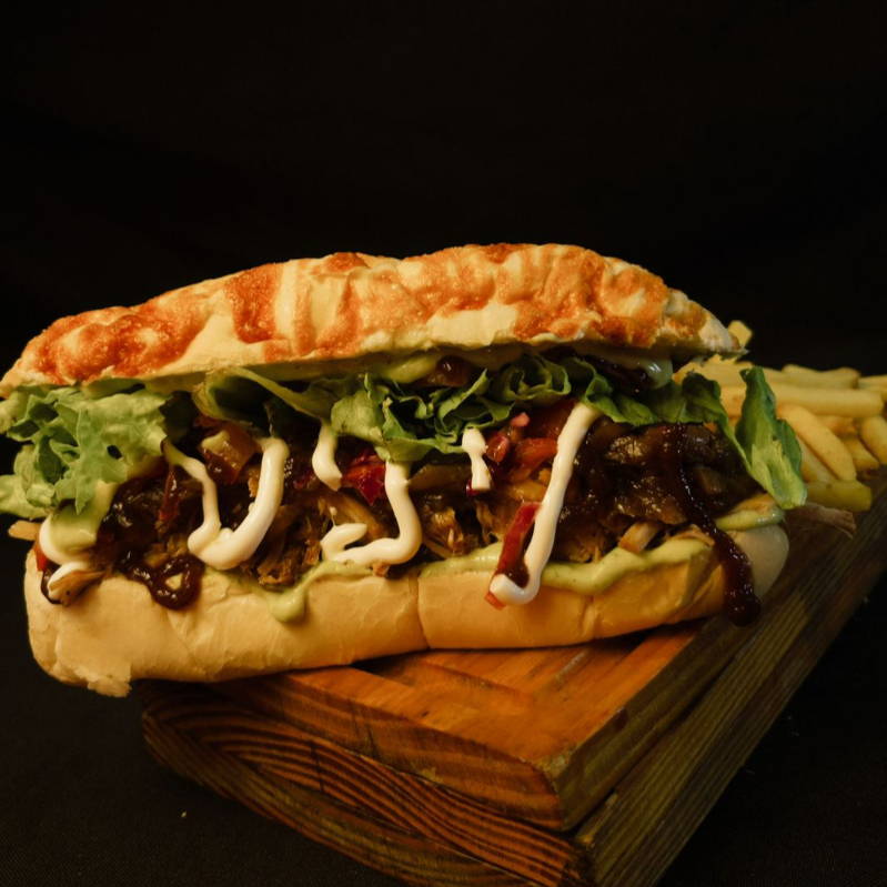 BAGUETE PARMESÃO, PERNIL DESTRINCHADO SUCULENTO, MOLHO DA CASA, QUEIJO, ABACAXI GRELHADO, RÚCULA