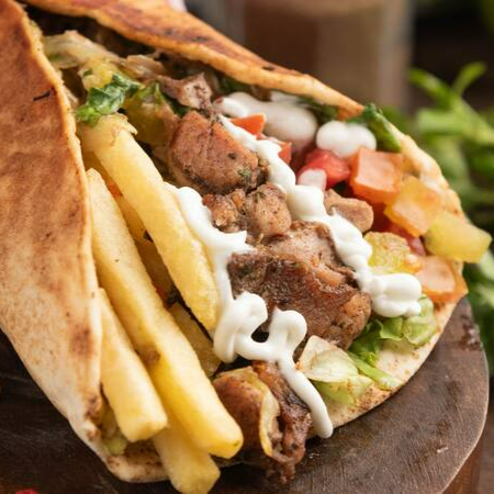 Descubra a sensacional experiência do nosso Shawarma, categoria 'Misto'. Este prato robusto é envolto em uma camada de pão sírio macio e leve. Em seu interior, encontra-se uma generosa porção de carne Bovina e Frango suculenta, meticulosamente temperada. Acompanha uma irresistível camada de creme de alho, que adiciona um sabor rico e cremoso. As batatas fritas crocantes inseridas dão um toque especial, enquanto os tomates frescos e a alface crocante proporcionam um saboroso contraste. Para completar, a cebola roxa acrescenta uma pitada de intensidade. Uma verdadeira explosão de sabores em cada mordida!