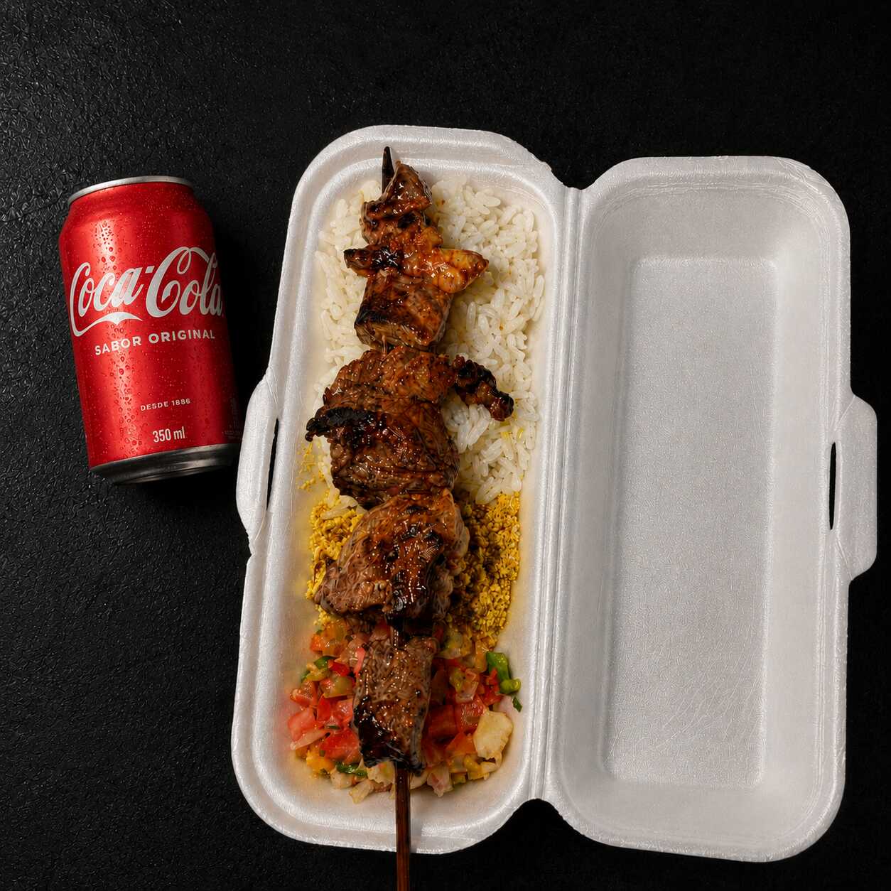 Espetinho suculento na brasa, servido com arroz, farofa e vinagrete fresquinho, acompanhado de uma Coca-Cola 350ml geladinha para completar a refeição com muito sabor.