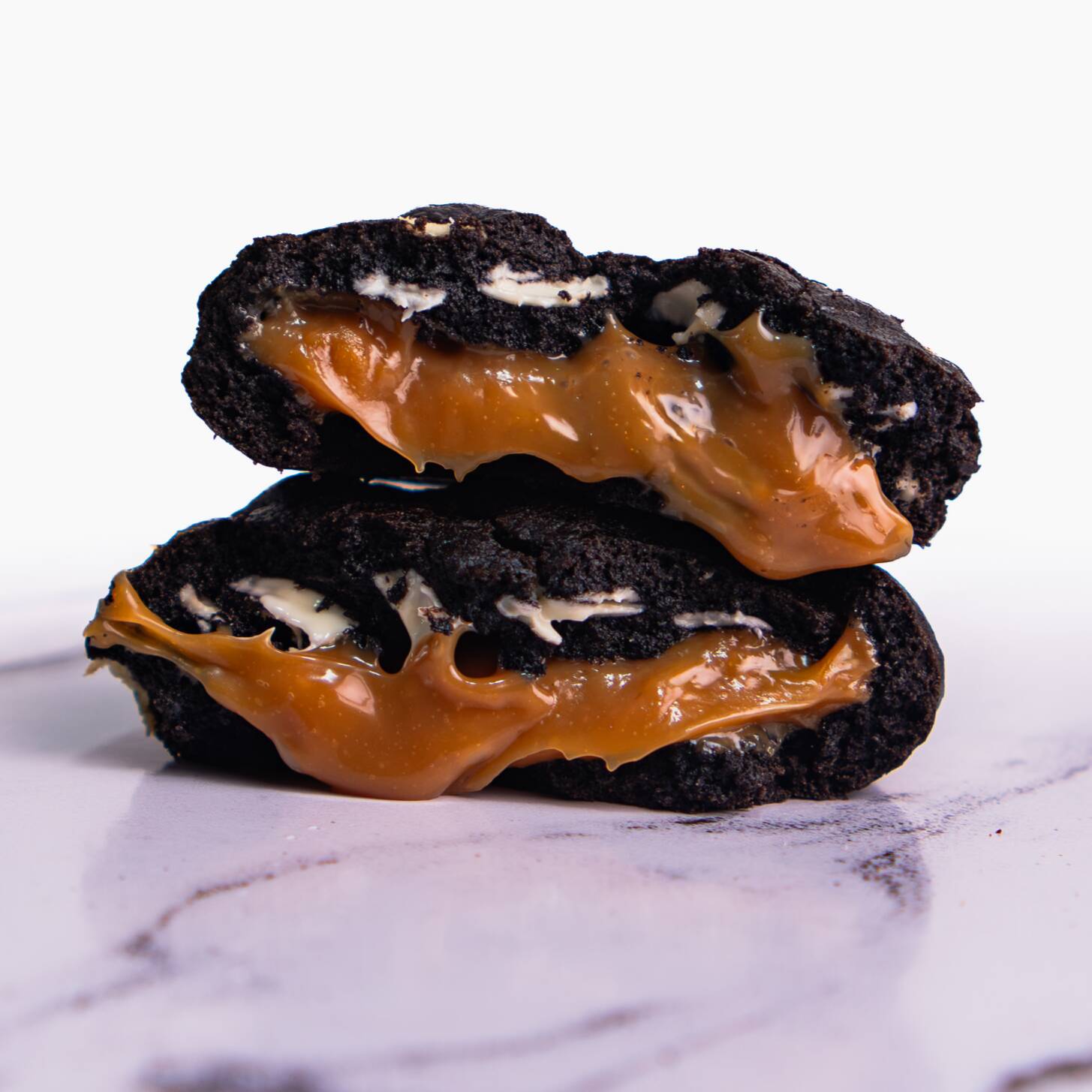 Nosso cookie de Caramelo Salgado é feito com massa de cacau black e gotas de chocolate nobre branco, recheado com um irresistível brigadeiro de caramelo salgado que equilibra doçura e leve toque de flor sal.