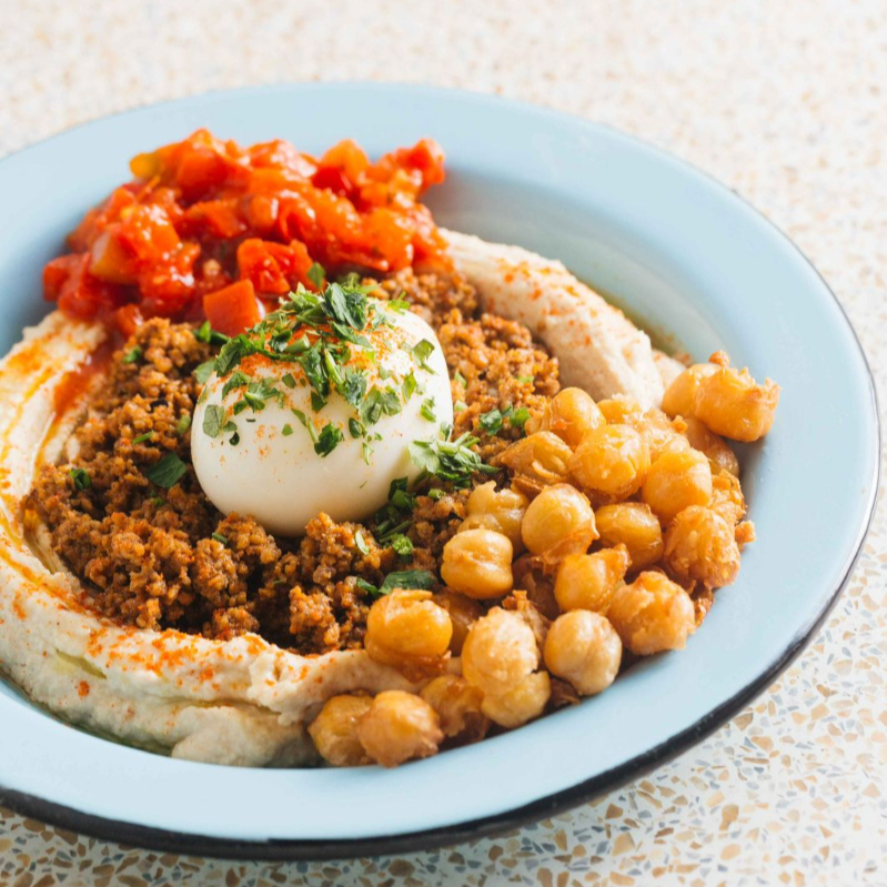 Hummus, carne moída temporada, grão-de-bico crocante, ovo mole, matbucha, azeite e páprica.