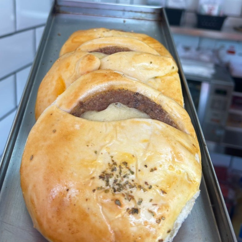 Recheio saboroso de hambúrguer artesanal combinado com queijo derretido e presunto fatiado, envolto em massa leve e assada até o ponto perfeito