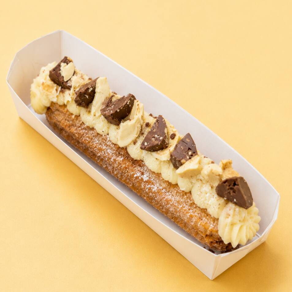 Churros crocante e macio por dentro, recheado e coberto com creme delicioso e pedacinhos de Sonho de Valsa — uma explosão de sabor irresistível!
