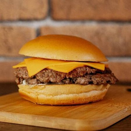 Pão, duplo smash de 80g (carne sem ponto, pois preensamos a carne na chapa criando uma deliciosa crostinha de sabor), fatias de queijo cheddar e maionese de alho poró.