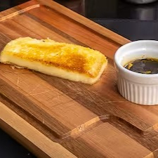 Queijo coalho grelhado, levemente dourado, servido com um toque de melado, trazendo uma combinação irresistível de sabores.