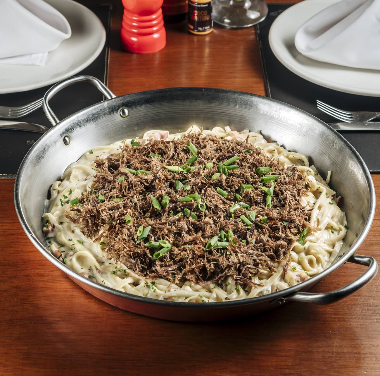 Carne de Sol desfiada grelhada sobre fettuccine com molho alfredo e bacon.