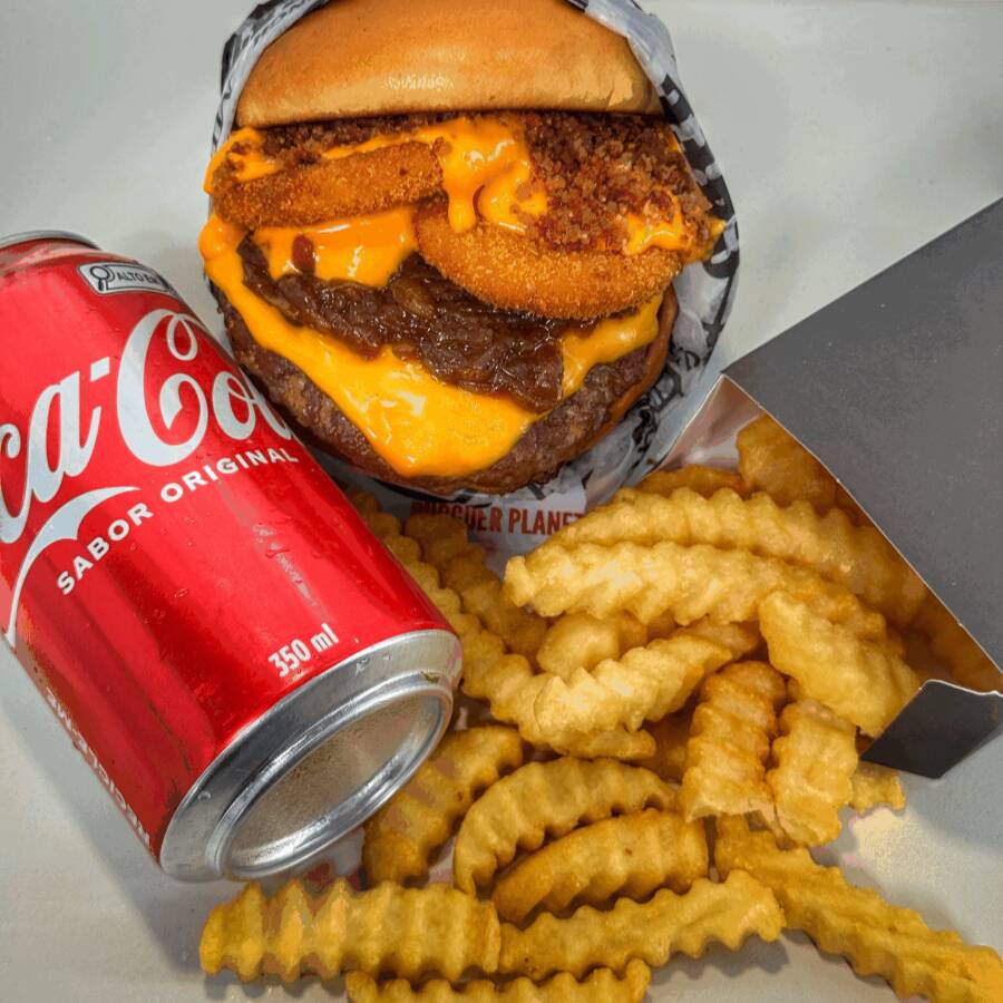 Pão brioche selado, hambúrguer bovino de 150g, cheddar derretido, cebola caramelizada, anéis crocantes de cebola com molho cheddar e pedacinhos de bacon. Uma explosão de sabores em cada mordida! Para acompanhar uma deliciosa porção de batata frita crinkle e uma bebida geladinha.