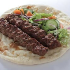 Dois espetos de carne moída assada, Pão Sírio ,pasta de alho, molho de tahine, tomate, picles, salsinha, acelga crespa, batata