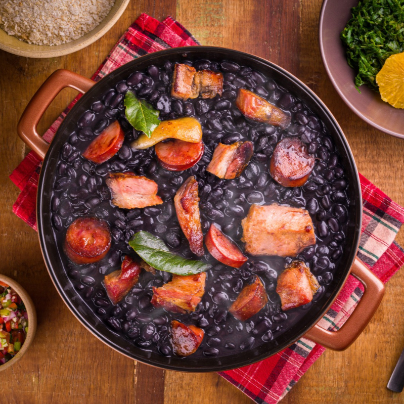 Desfrute da autêntica essência brasileira com a nossa Feijoada Completa. Este divino cozido de feijão preto é enriquecido com a textura única da pele suína e repleto de pedaços suculentos de paio, linguiça e bacon, todos harmonizados à perfeição com carne seca e costelinha que derrete na boca. Acompanhada de arroz branco soltinho , couve refogada com alho frito que estimula o paladar, torresmo crocante a cada mordida e uma farofa irresistível (Serve 1 pessoas)