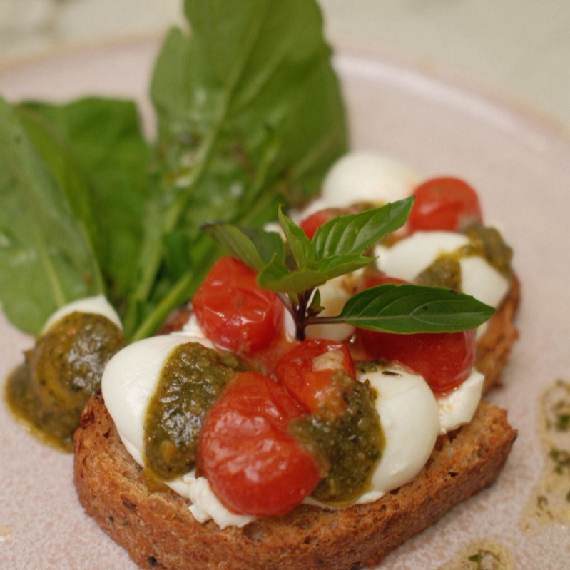 Combinação perfeita de tomate confitado no azeite, mussarela de búfula, pesto e pão tostado, acompanhado de rúcula.