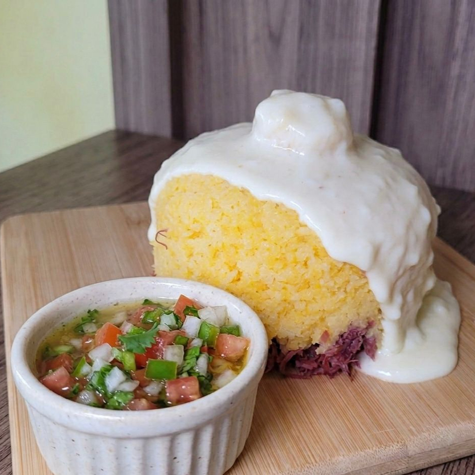 Cuscuz com carne seca desfiada coberto por creme de queijo.Acompanha molho vinagrete..