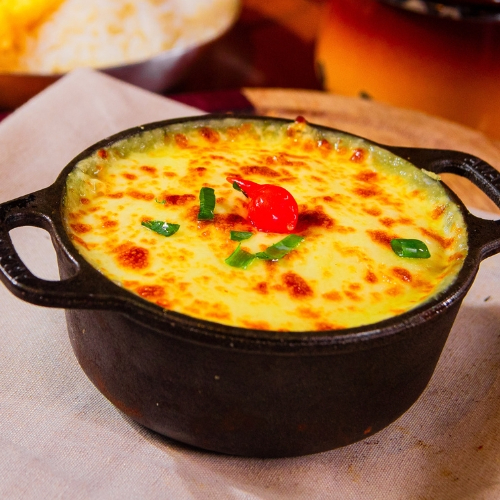 Escondidinho preparado a base de mandioca recheado com carne seca e requeijão, servido com arroz branco e batata chips.