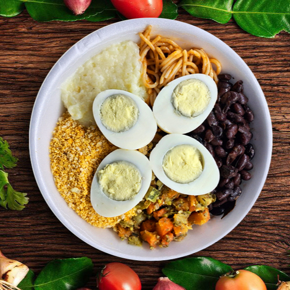 Arroz, Feijão, Farofinha temperada, Legumes do Dia, Macarrão, Purê de Batata e 2 Ovos Cozidos (Peso total 500g). Atenção: Utilizamos Bacon no tempero do feijão e farofa.