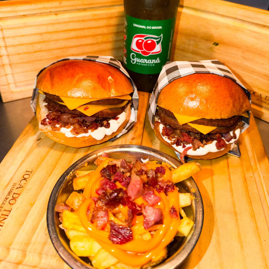 Pão de Brioche super macio, 2 burguer brasa( Industrial) de 56g, fatias de cheddar, bacon fatiado e molho da casa. (Acompanha Fritas cheddar e bacon + refrigerante 0,500ml))