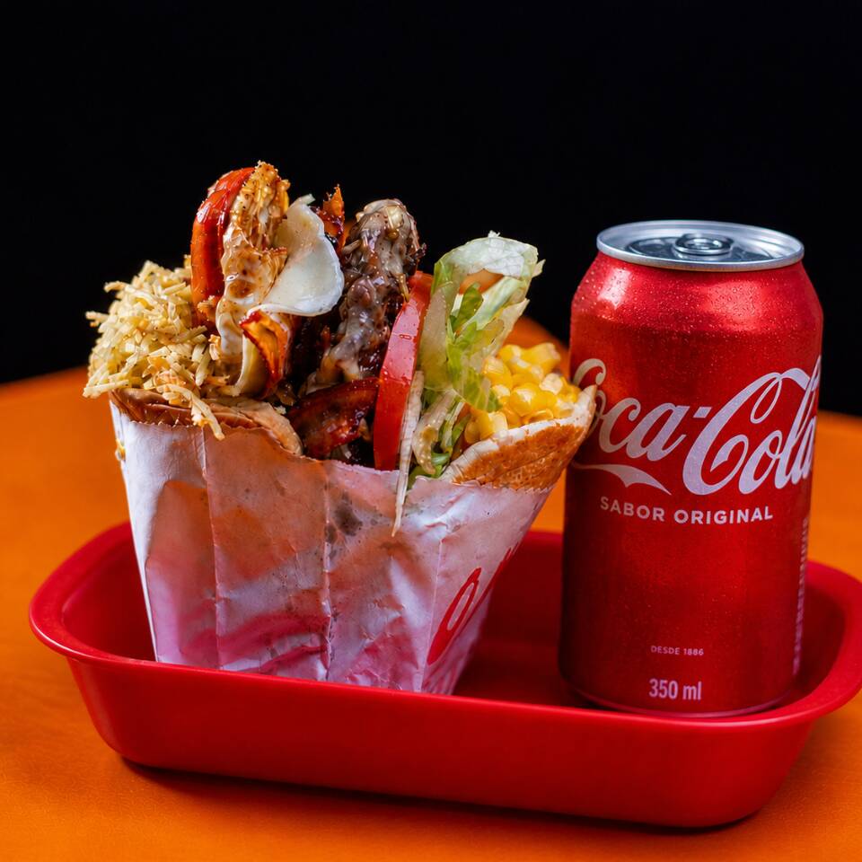 Um X-Tudo completo com muçarela, salsicha, bacon, ovo, alface, tomate, batata palha e milho, acompanhado de refri lata 350ml. O combo perfeito para matar a fome!