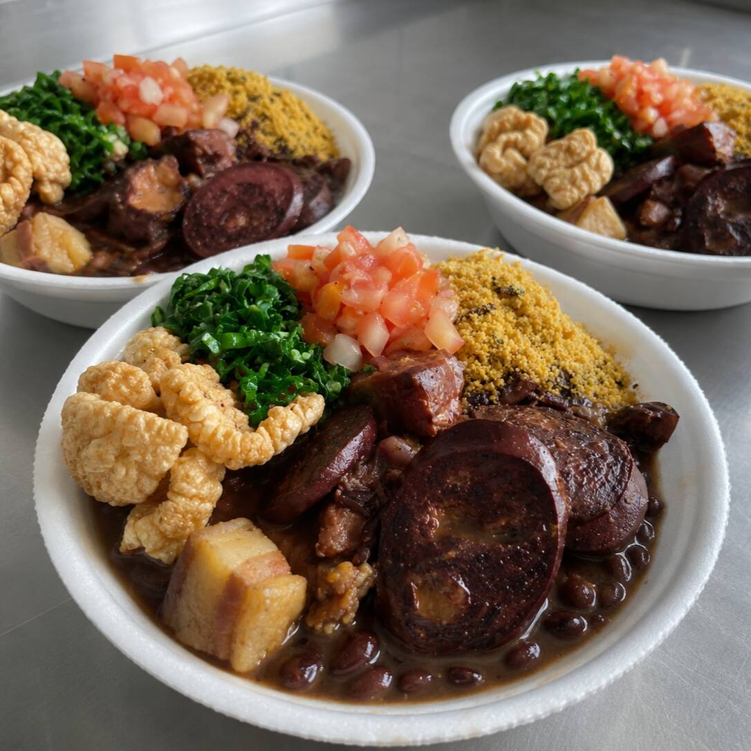 Nossa feijoada vem completa: feijão preto bem temperado, arroz soltinho, couve refogada, farofa crocante, vinagrete fresquinho e torresmo sequinho. Sabor de comida feita com carinho. Marmita Pequena - serve 1 pessoa. Escolha outra marmita para completar seu combo.