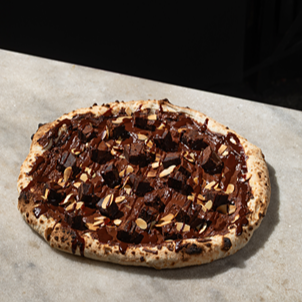 Pizza de Chocolate meio amargo, cubos de brownie, amêndoas torradas crocantes, finalizado com uma calda de chocolate meio amargo.