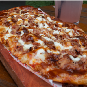 Molho de tomate da casa, muçarela, pernil suíno desfiado (cozido lentamente com especiarias), compota de abacaxi na cachaça, cream cheese e molho barbecue de cerveja sour