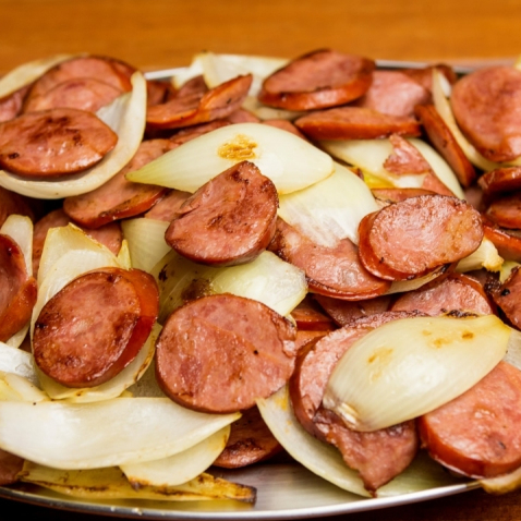 Finas fatias de calabresa defumada grelhada e acebolada com vinagrete e cesto de pães fatiados