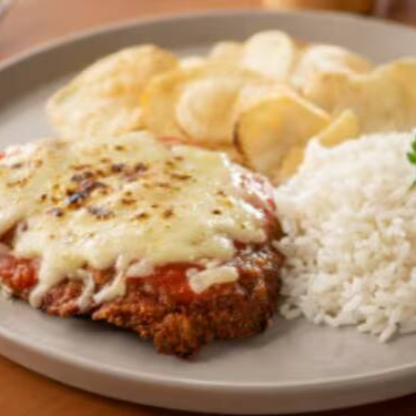Será a melhor Parmegiana que você irá comer em sua vida, com molho de tomate artesanal e uma camada de queijo derretido. Acompanhado de batata chips, arroz, feijão e farofa. Foto meramente ilustrativa. Não é possível modificar o prato. O feijão é enviado em uma embalagem de 140gr separada.