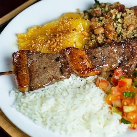 Arroz branco soltinho, feijão tropeiro bem recheado, vinagrete fresco, mandioca cozida e um espeto de contra-filé assado na brasa.
