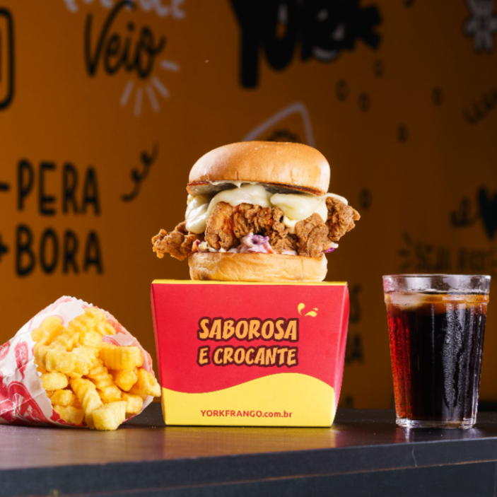 Fabuloso Lanche York preparado no pão Brioche, com melhor Frango Frito Crocante, Salada Coleslaw, Queijo e Molho. Acompanha Batata Frita Individual + Refrigerante Lata. Foto Ilustrativa.