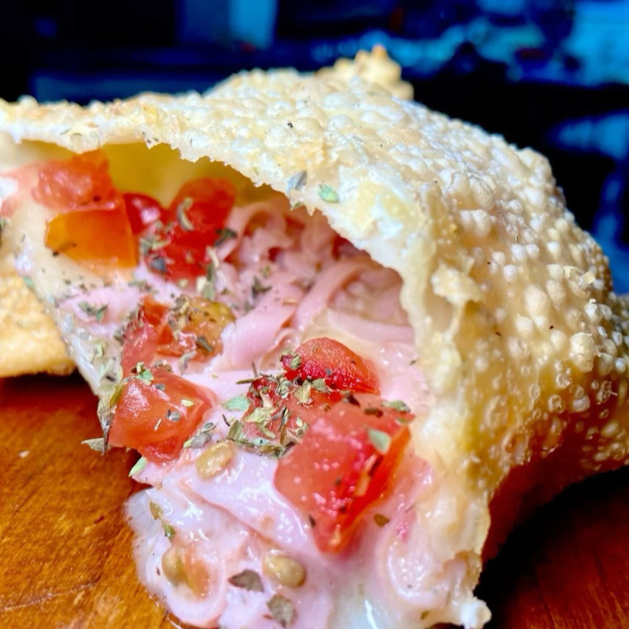 Aprecie o pastel de pizza simples, recheado com queijo, presunto e orégano, trazendo o sabor da pizza em cada pedaço.