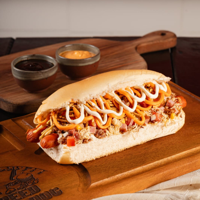 Pão de 20 cm prensado na chapa, 2 salsichas (PERDIGÃO), frango desfiado, bacon premium, lombo defumado, maionese, batata palha, Cheddar e cream chesse.