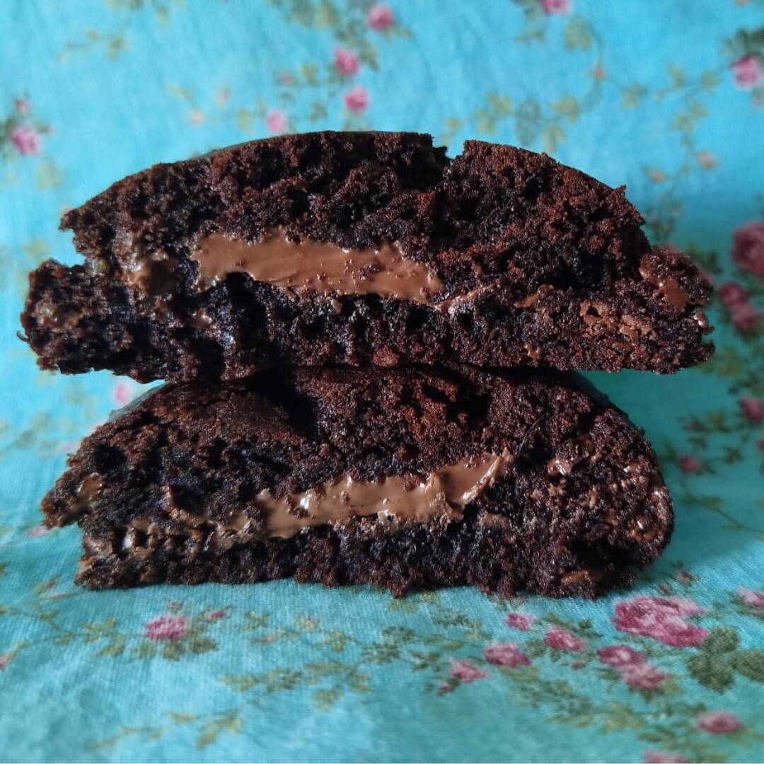 Cookie artesanal de 90g assado na hora com massa de chocolate, com cacau 100% e gotas de chocolate nobre meio amargo, recheado com creme de avelã, equilibrado no ponto perfeito para derreter na sua boca a cada mordida.