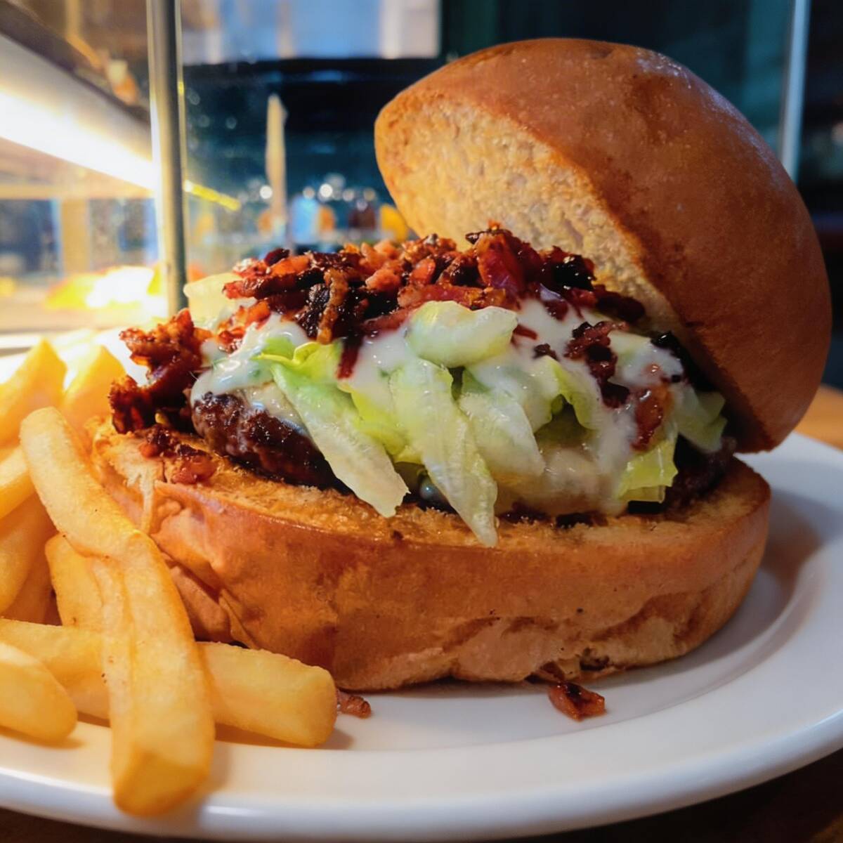 Pão de hamburguer tostado na chapa, haburguer da casa, bacon crocante, queijo, alface e molho ranch, acompanha fritas.