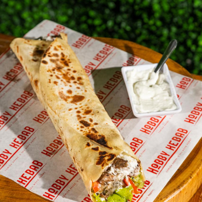 Pão sírio de 25cm com carne temperada com especiarias árabes, alface fresco, tomate maduro e cebola temperada. Acompanha o molho de alho caseiro.