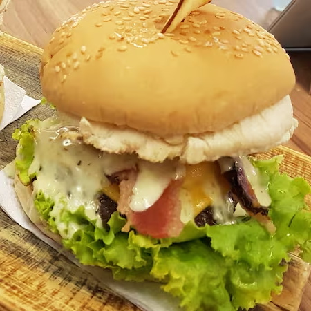 Pão de hambúrguer com gergelim, hambúrguer 120g , cheddar , bacon, picles, anel de cebola , alface , tomate e molho de ervas
