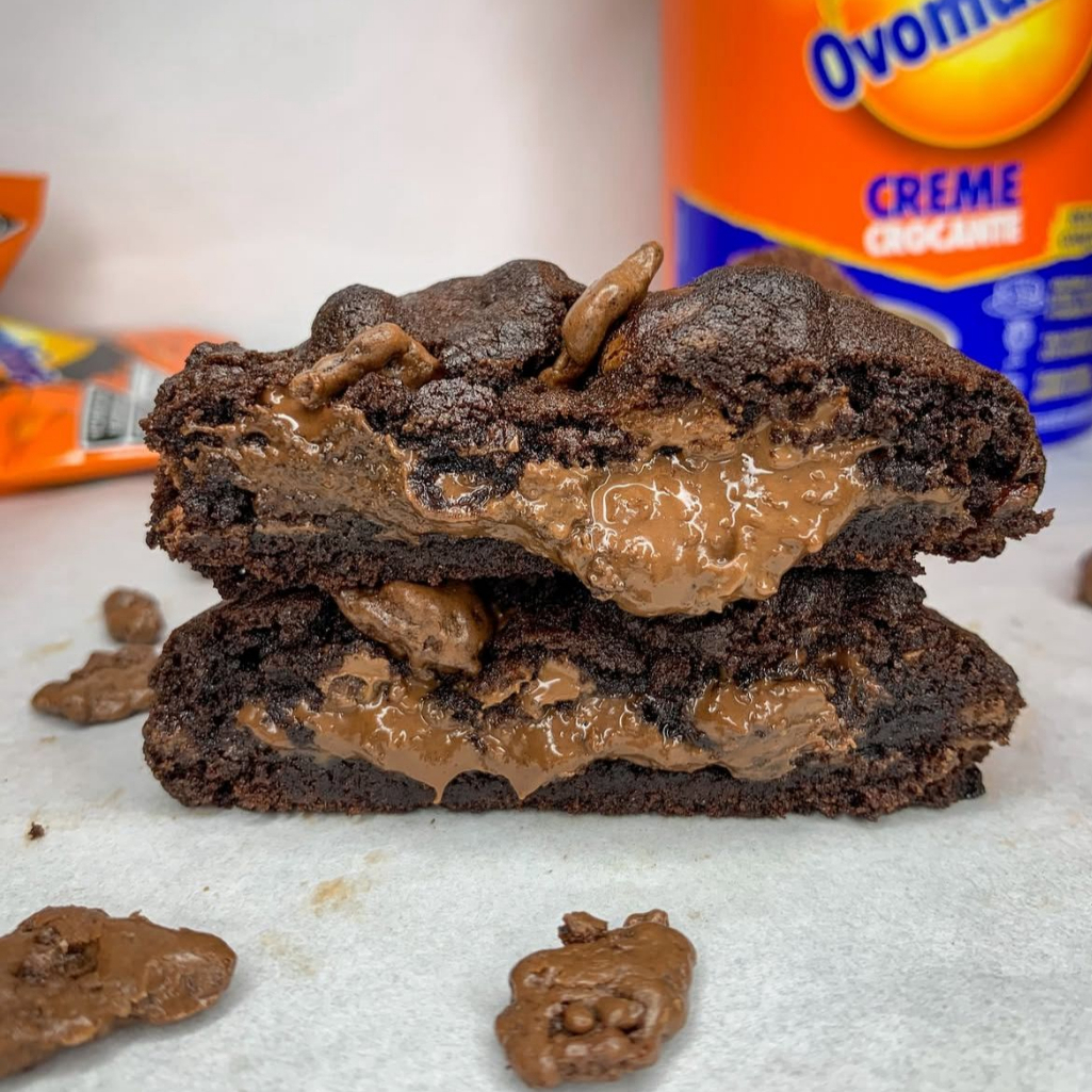 Massa de cacau, gotas de chocolate ao leite, recheado com creme de Ovomaltine, finalizado com Ovomaltine Rocks.