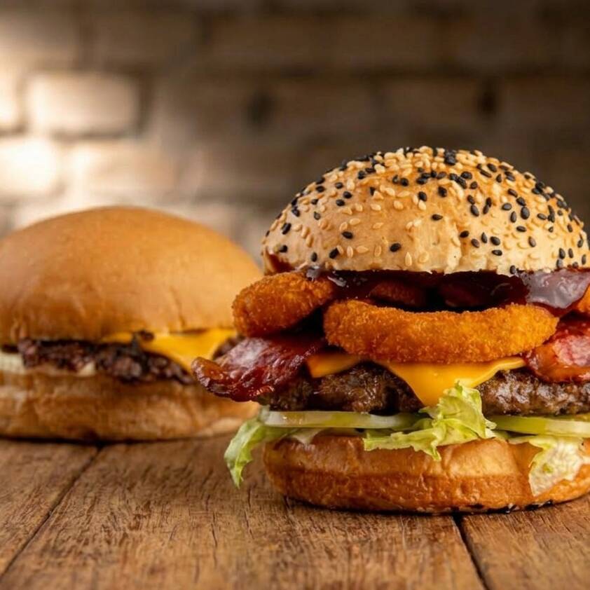 Pão com gergelim selado na manteiga de bacon. No recheio, um hambúrguer de 180g* ou 120g* com blend 100% angus, grelhado no fogo e cheio de suculência. O cheddar derrete no ponto certo, o bacon entra crocante, e o molho barbecue dá o toque defumado que amarra tudo. Alface e tomate garantem o frescor, e as onion rings trazem aquele crunch que faz toda a diferença.