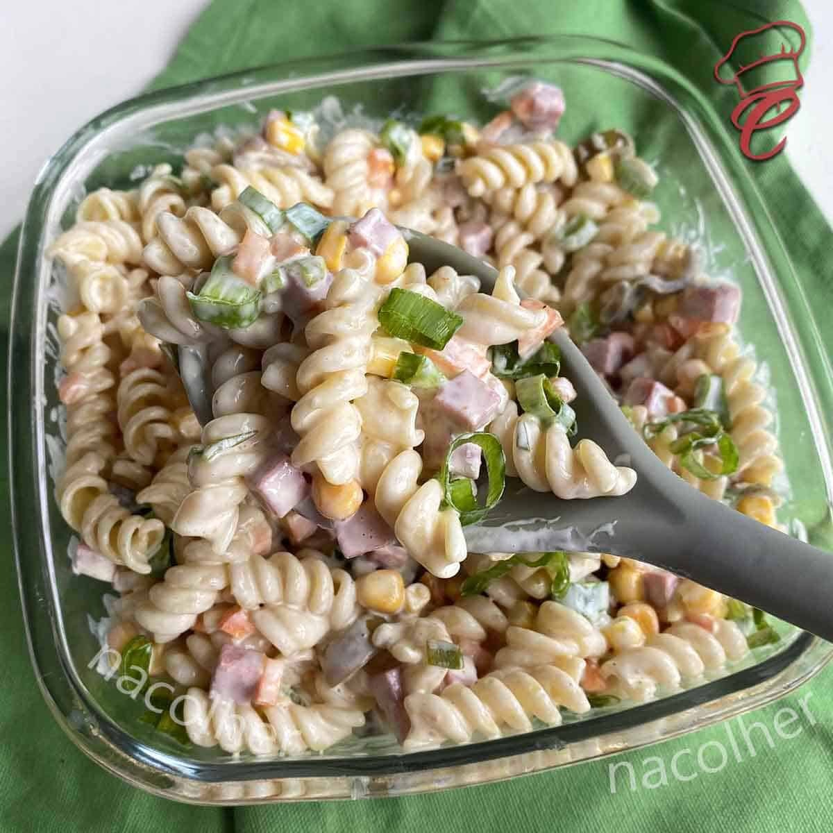 Salada de macarrão com cenoura, azeitonas, milho, uva passsas e maionese.