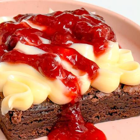 Brownie chocolatudo coberto com brigadeiro de leite Ninho cremoso e geleia artesanal de morango. tamanho 7x7cm