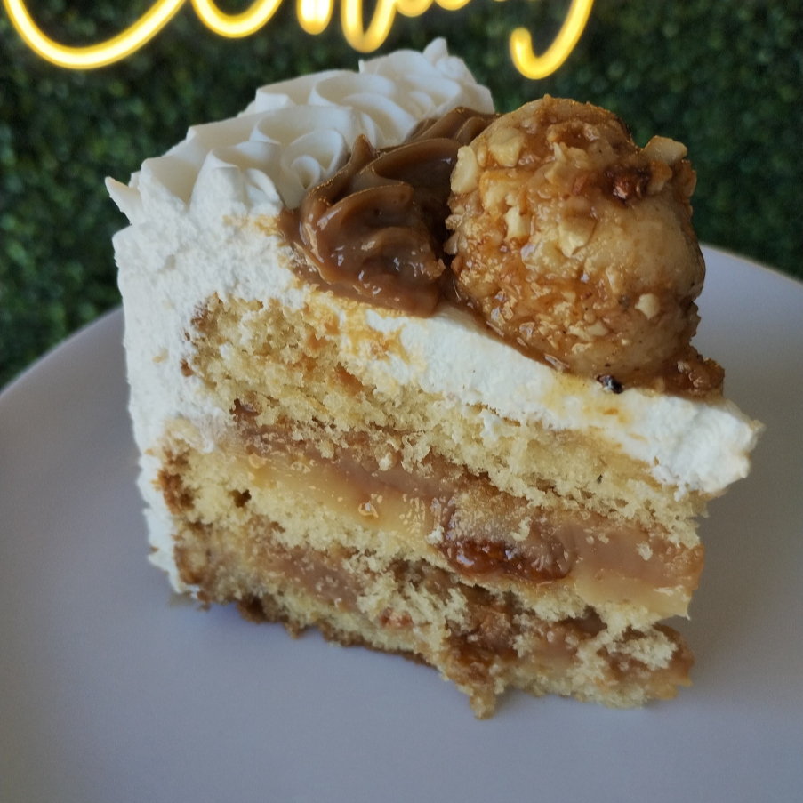 Massa branca, recheio de brigadeiro branco, doce de leite, crocante de castanha e cobertura de chantininho. Peso da fatia aprox 180g.