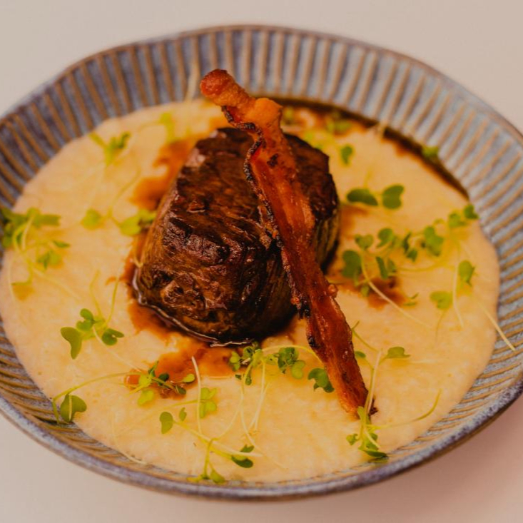 Acompanhado de risoto de queijo grana padano, crocante de bacon e brotos de rúcula.