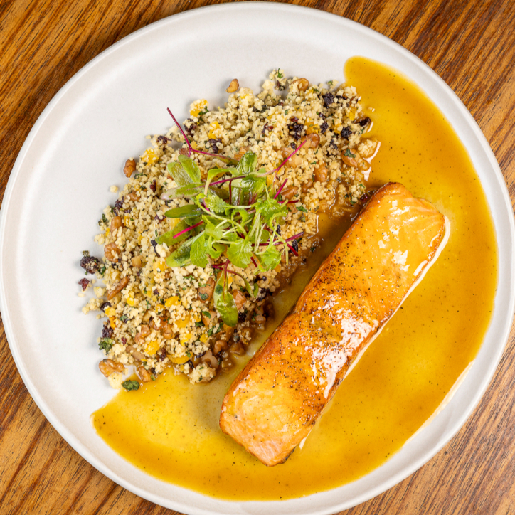Salmão grelhado ao sumo de laranja fresca, servido com couscous marroquino aromatizado com hortelã, damascos, uvas-passas e raspas cítricas e nozes.