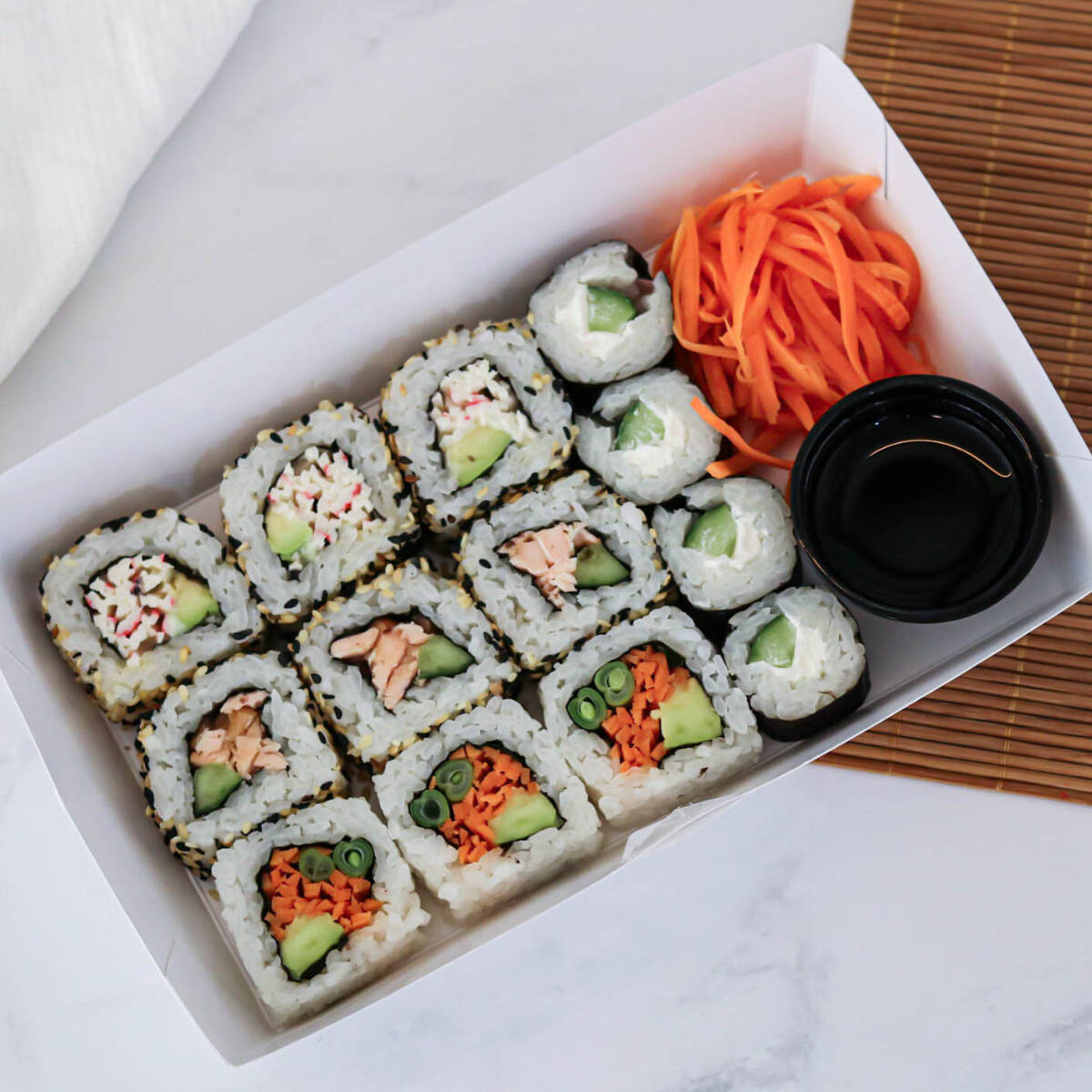 Salmão grelhado, kani kama, cenoura marinada, vagem no vapor, hortelã, avocado, pepino, cream cheese, arroz de sushi, alga nori, shoyu, gergelim.