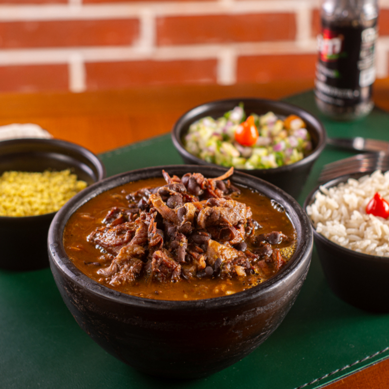 Parece uma feijoada, mas não é, esse feijão adubado é muito melhor, porque acompanha: feijão preto, recheado com patinho, charque, calabresa, paio, bacon, costelinha e pedaços de maminha, acompanhado de arroz, farofinha acebolada, vinagrete e limão